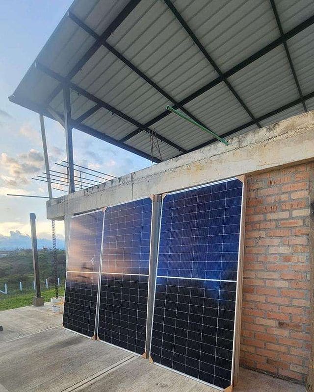 Tres paneles solares de Foster Green Energy apoyados contra el muro de una construcción, al atardecer